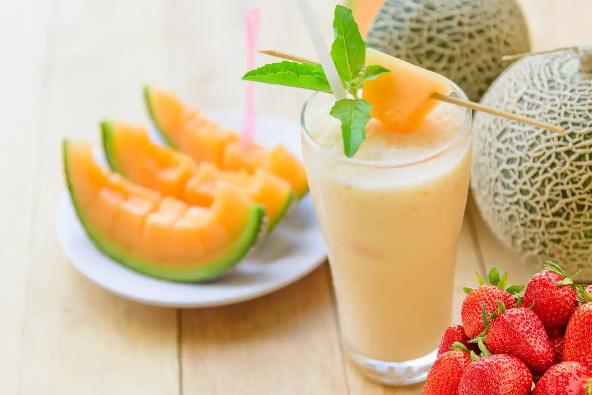 mesa con vaso de agua de melón con fresa