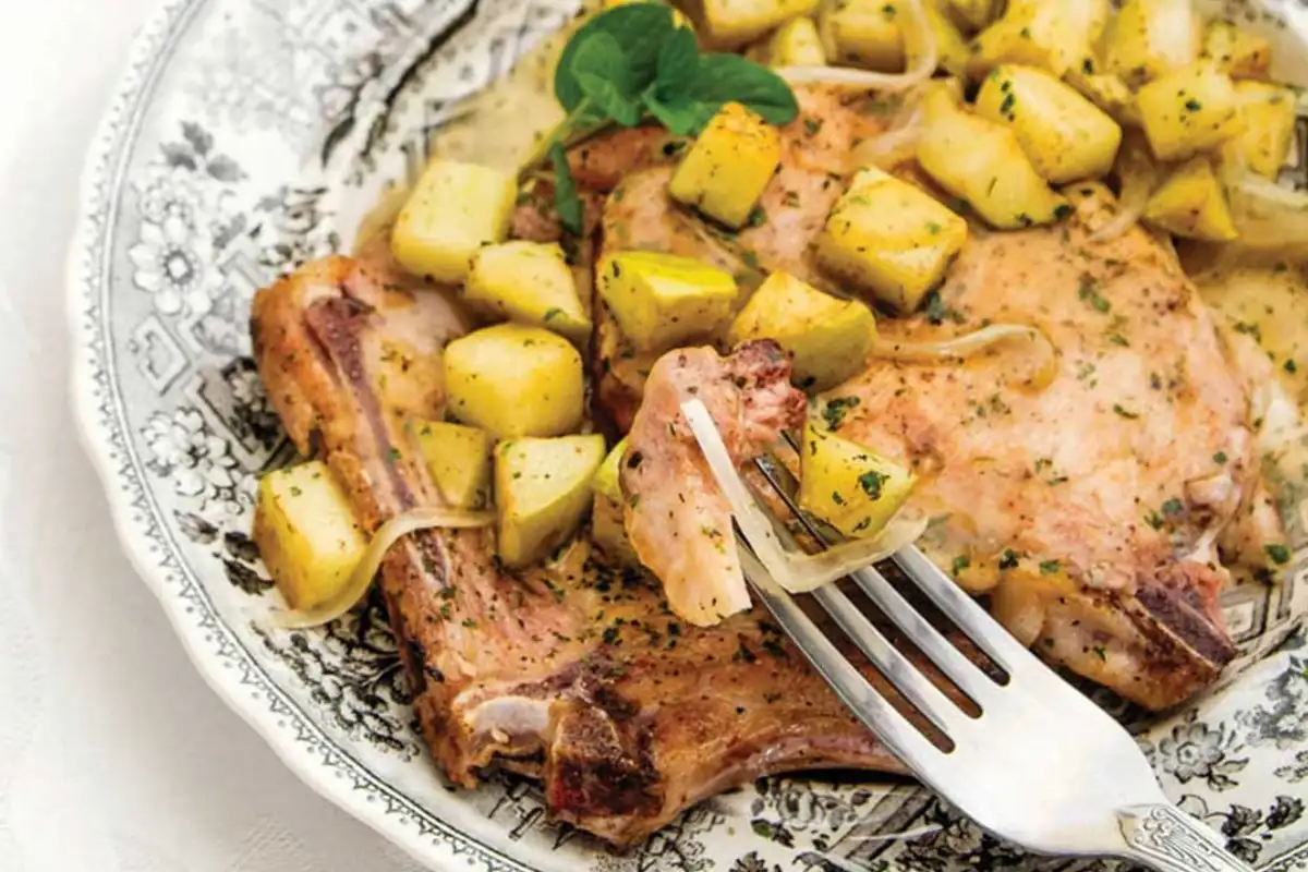 Un tenedor sostiene un pedazo de chuletas ahumadas con papas