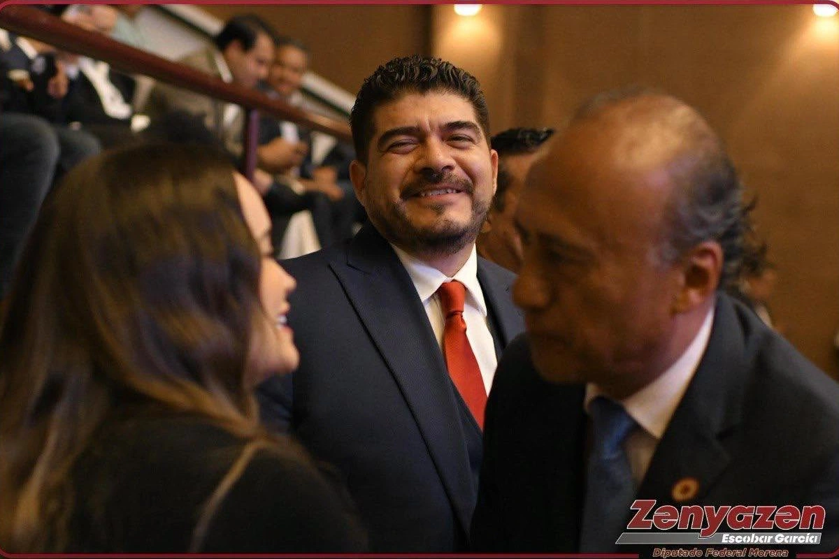 El diputado Zenyazen Escobar García sonriendo de traje oscuro y corbata roja mientras interactúa con otras personas en el recinto legislativo.