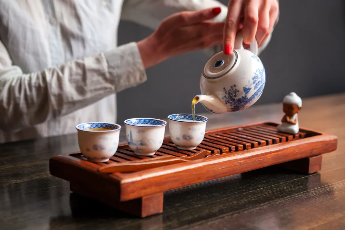 Persona sirviendo té en tazas de porcelana