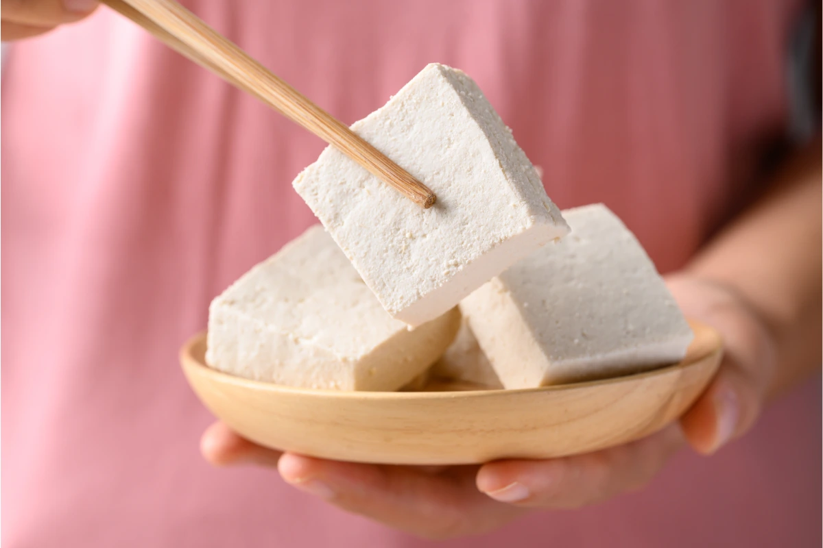 Mujer toma un trozo de tofu con palillos chinos